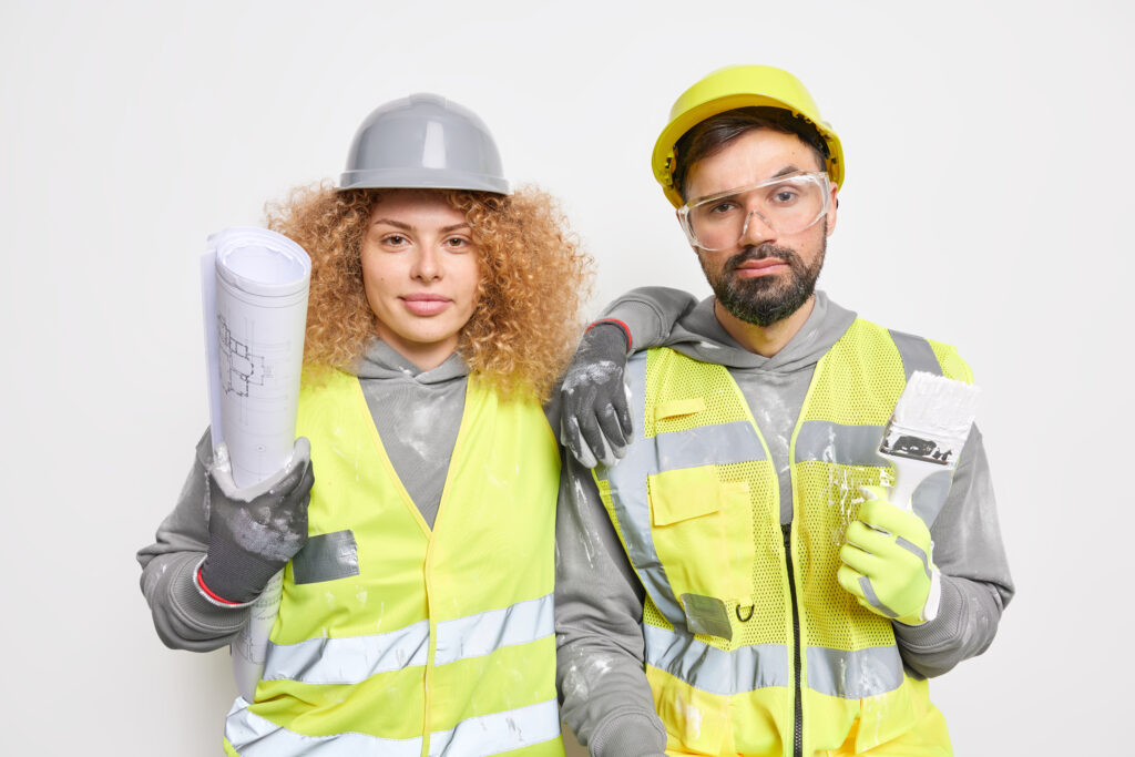 Team of professional architects dressed in uniform work together hold blueprint and paint brush work for building construction project come on site isolated over white background. Two engineers